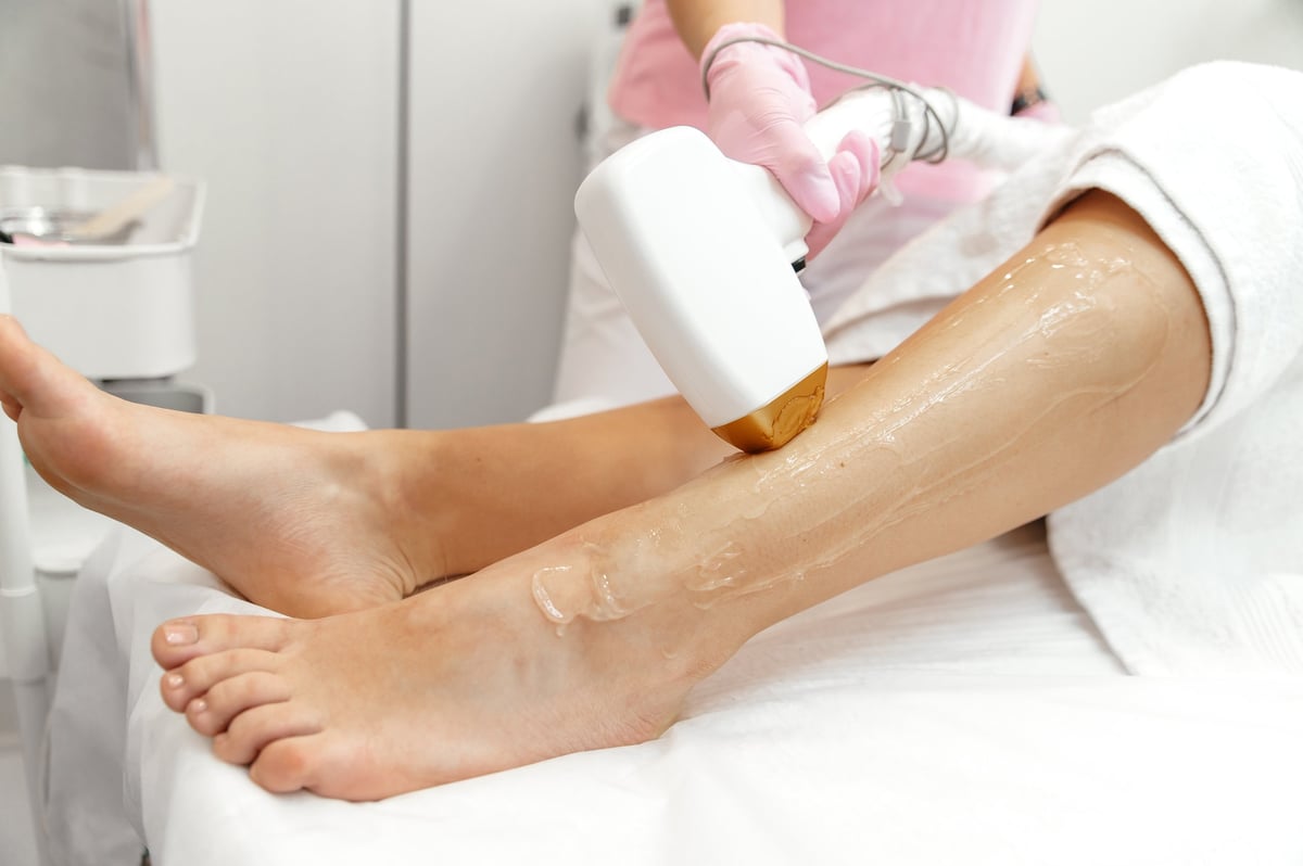 Aesthetic cosmetology. Laser epilation and cosmetology. Hair removal cosmetology procedure. Caucasian woman doing a procedure to remove unwanted hair on her legs using a laser in a beauty salon