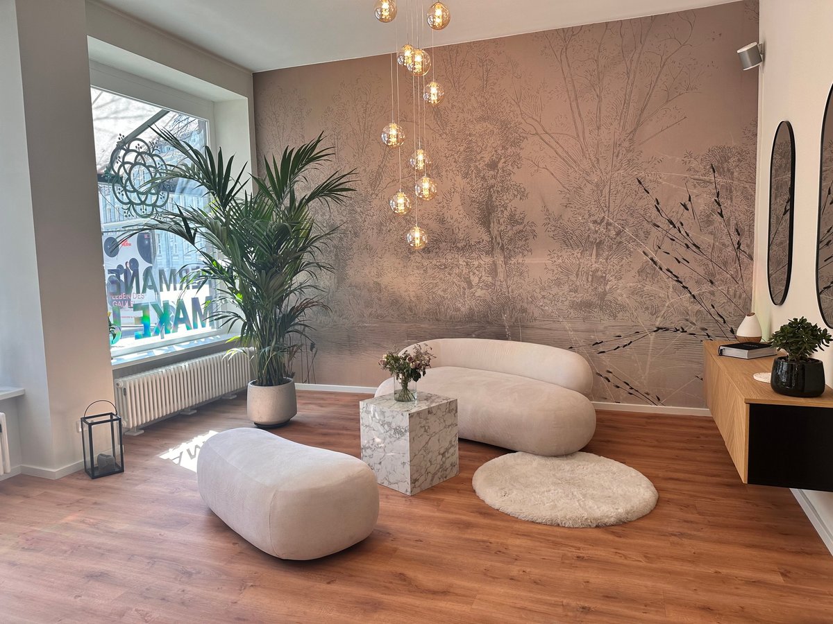Modern lounge space with cream curved seating, wooden floors, potted plants, pendant lights, and textured wall art